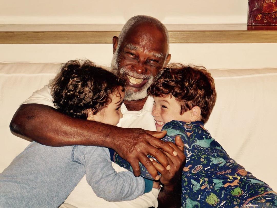 Grandpa Ole smiling as he hugs two young grandchildren